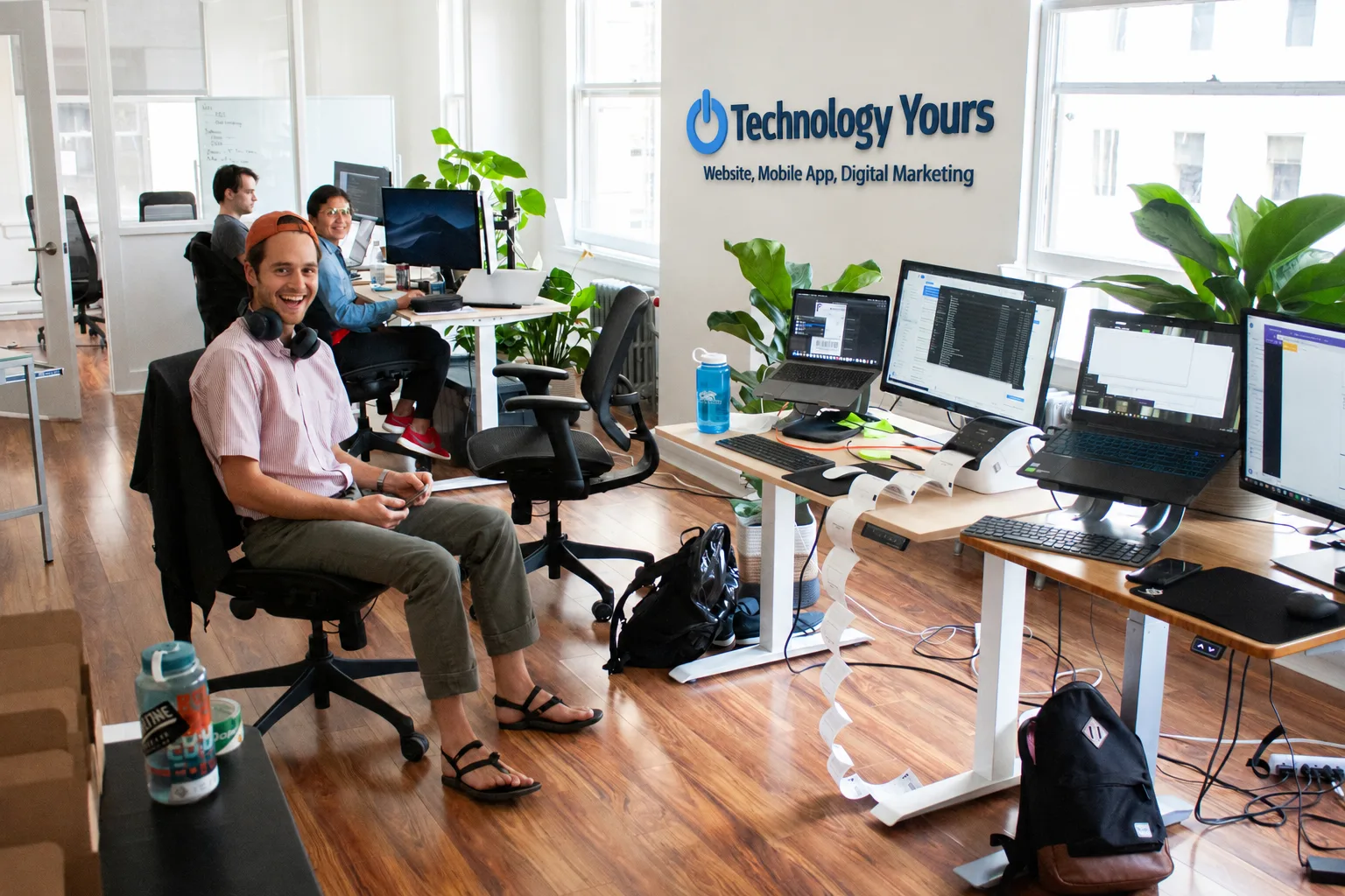 Technology Yours team at work in the office beneath the company wall sign